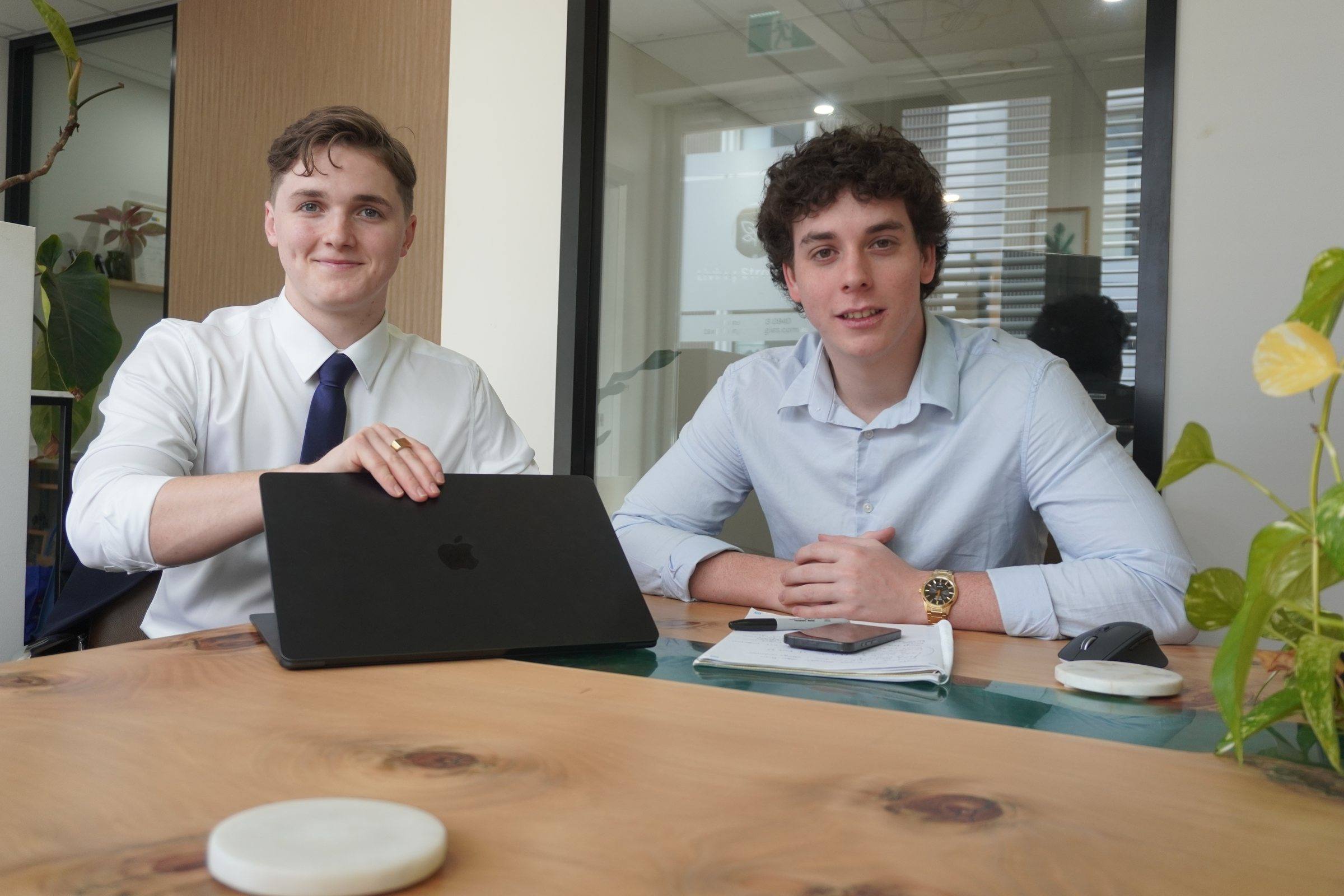 Zeek and Levi sitting at a desk, smiling at the camera